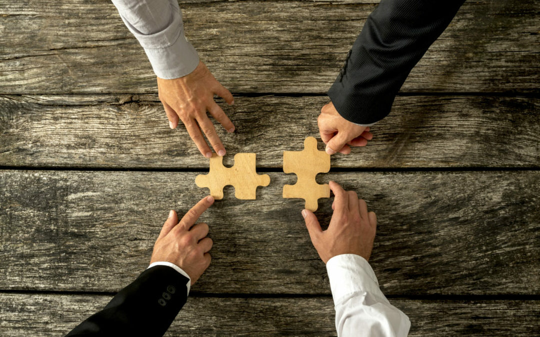 Hands placing puzzle pieces together symbolic of mergers and acquisitons
